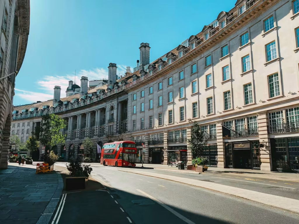 Curved terrace of white stone buildings on a London street with a red bus