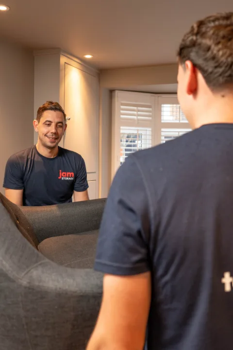 Two JamStorage crew members carrying a sofa through a customer’s home