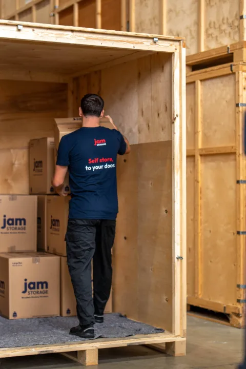 JamStorage crew member loading boxes into a wooden Jam Pod storage container